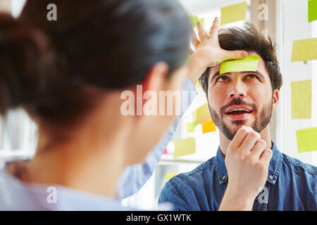 Junger Mann im Team-building-Spiel mit Notiz auf Stirn mit einer Idee Stockfoto