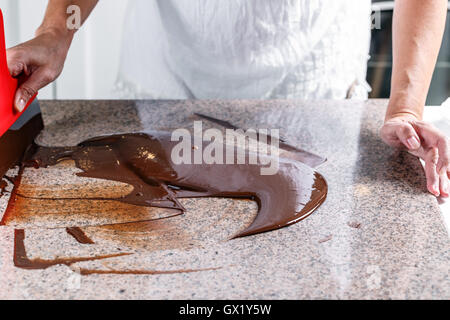 Temperierung geschmolzenen Schokolade auf Tisch Stockfoto
