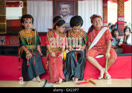 Gruppe von jungen Toraja spielen eine Gadget-Pose für Kamera mit Tracht bei einer Beerdigungszeremonie während der Rambu Solo Stockfoto