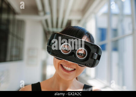 Nahaufnahme Schuss der fröhliche junge Frau, die virtual-Reality-Brille tragen. Weibchen mit VR Kopfhörer Anschlussvorrichtung. Stockfoto