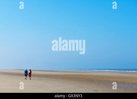 Paar zu Fuß entlang einem einsamen Strand in Titchwell, North Norfolk, England UK Stockfoto