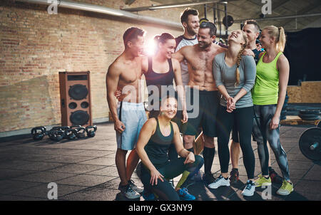 Gruppe von acht glückliche muskulöse weibliche und männliche Erwachsene zusammenstehen als gute Freunde im Fitness-Studio mit großen Lautsprecher im Hintergrund ein Stockfoto