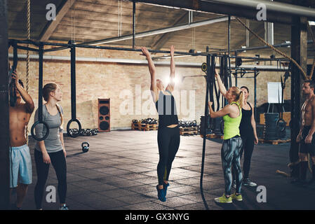 Gruppe von jungen männlichen und weiblichen Erwachsenen tun ziehen ups auf bar-cross-Fit Training Fitness-Studio Stockfoto