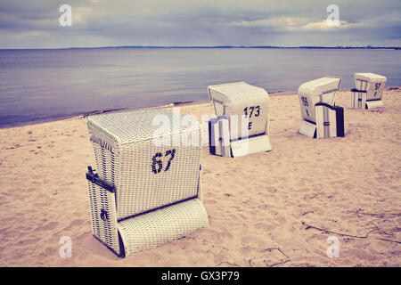 Vintage getönten Kapuzen Korbsessel Korb an einem leeren Strand. Stockfoto