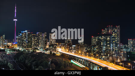 Glühende Stadtbild und Bauwerke als helle Streifen entlang Gardiner Expressway in einer heißen & schwülen Sommernacht in Toronto am See. Stockfoto