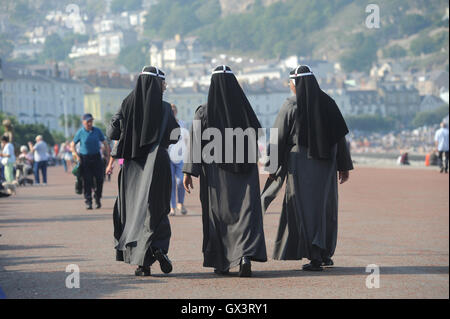 FRAUEN IN RELIGIÖSER KLEIDUNG ZU FUß WIEDER RENNEN RASSISTISCHE GEMEINSCHAFT MULTI KULTURELLE BURKA STIL BEDECKT KOPF KLEID INTEGRATION BRITISCHEN UK Stockfoto