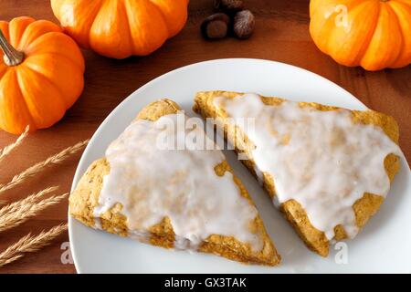 Süß Herbst Kürbis Scones mit Zuckerguss, auf Teller mit Holz Hintergrund Stockfoto
