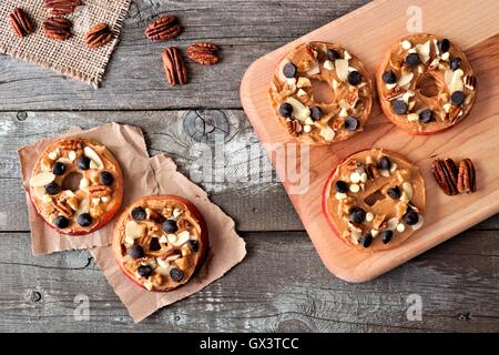 Im Herbst Apfel rundet mit Erdnussbutter, Schokolade-Chips und Nüssen, nach unten gerichtete Blick auf rustikalen Holz Stockfoto