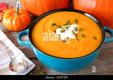 Cremige Kürbissuppe, garniert mit Kürbiskernen und Sahne in eine blaue Schüssel hautnah Stockfoto