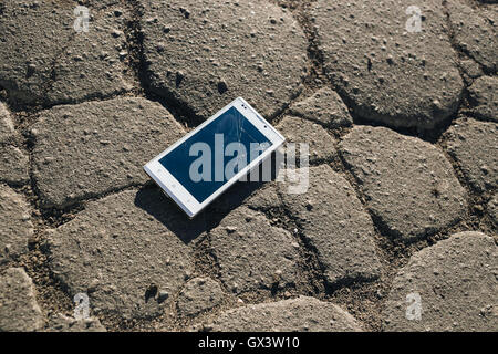 Telefon mit gebrochenen Bildschirm auf Asphalt. Jemand ließ Gerät Stockfoto