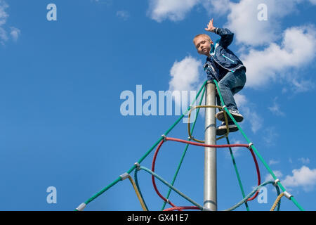 Der Junge kletterte auf der Oberseite einen Spielplatz Stockfoto