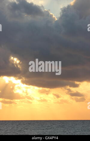 Ein wunderschön Moody Himmel mit der Sonne hinter den Wolken, bei Sonnenuntergang, mit dem Meer Stockfoto