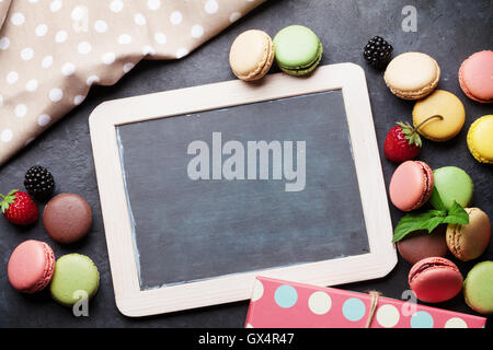 Bunte Makronen und Blackboard. Süßen Macarons am Steintisch. Draufsicht mit textfreiraum für Ihren text Stockfoto