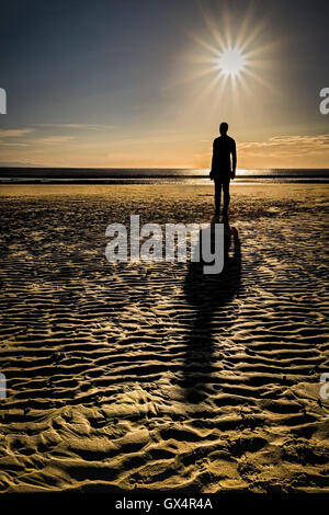 Ein Bild von einem der Anthony Gormley Statuen wie die Sonne war an Crosby Strand in Liverpool hinunter. Stockfoto