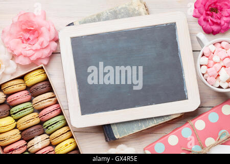 Bunte Makronen und Blackboard. Süßen Macarons in Geschenkbox auf Holztisch. Draufsicht mit textfreiraum für Ihren text Stockfoto