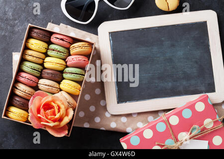 Bunte Makronen und Blackboard. Süßen Macarons in Geschenk-Box am Steintisch. Draufsicht mit Textfreiraum Stockfoto