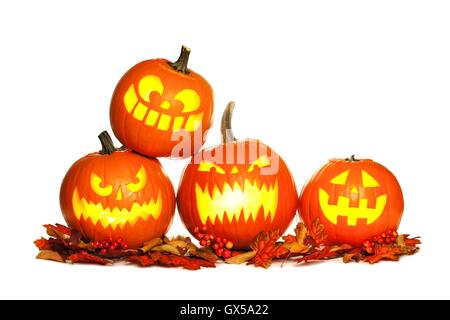 Gruppe von Spaß beleuchtet Halloween Jack-o-Laternen mit Herbstlaub isoliert auf einem weißen Hintergrund Stockfoto