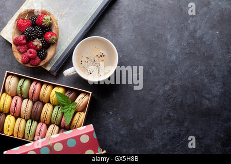 Bunte Makronen und Beeren am Steintisch. Süßen Macarons und Kaffeetasse. Draufsicht mit Textfreiraum Stockfoto