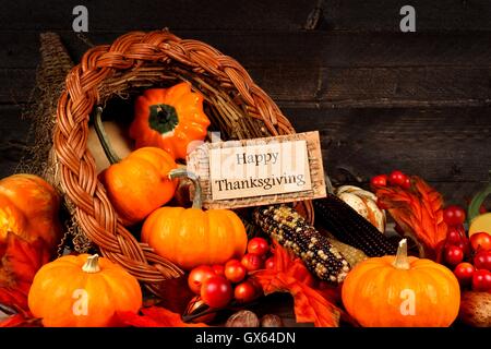 Ernte Füllhorn hautnah mit Happy Thanksgiving Geschenkanhänger auf dunklem Holz Stockfoto