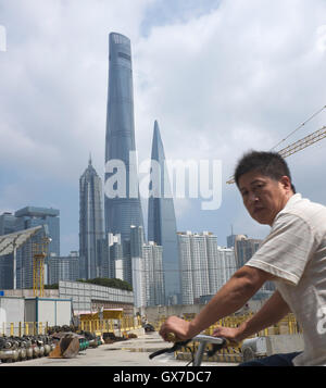 Ein chinesischer Mann fährt Fahrrad vorbei an Hochhäuser von Pudong in Shanghai, China. 12 Sep 2016 Stockfoto