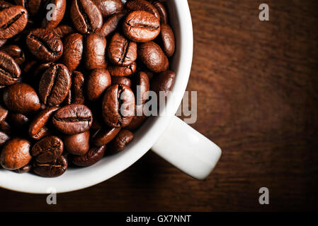 Frische Kaffeebohnen im Cup auf hölzernen Hintergrund Stockfoto