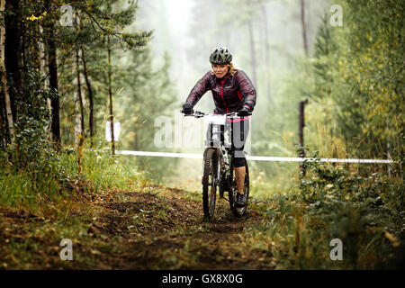 Junge, blonde Frau Radfahrer reitet auf einem Waldweg bei regionalen Wettkämpfen auf cross-country-bike Stockfoto