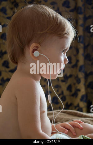 Clouse-Up Portrait schöne glückliches Baby mit Kopfhörern Musik hören. vertikale Stockfoto