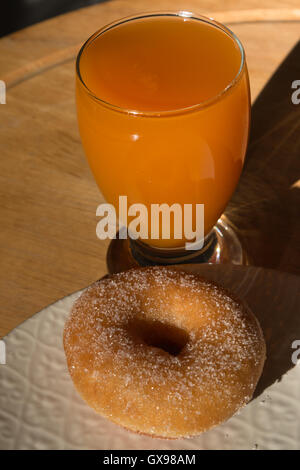 Fried-Donut in weißen Teller und Glas Aprikosensaft Stockfoto