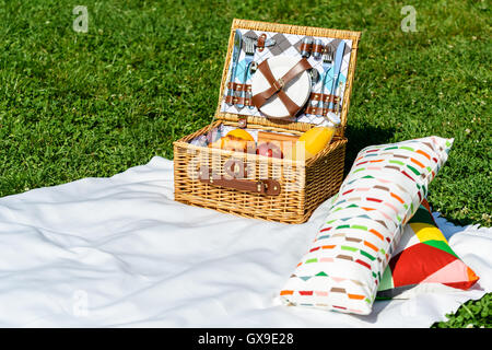 Picknick Korb Essen auf weißen Decke mit Kissen im Sommer Stockfoto