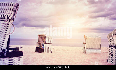 Lila Vintage getönten Kapuzen Korbsessel Korb an einem leeren Strand. Stockfoto