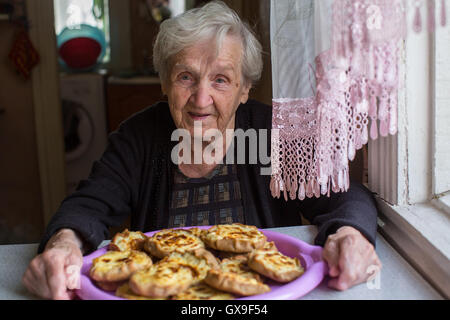 Großmutter mit Kuchen in der Küche. Stockfoto