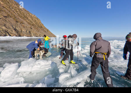 Baikalsee, Russland, März 24. Die Überfahrt durch den Spalt im Eis der Baikalsee großen touristischen Gruppe Menschen Eislaufen und Stockfoto