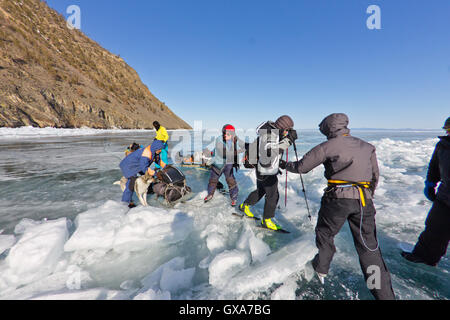 Baikalsee, Russland, März 24. Die Überfahrt durch den Spalt im Eis der Baikalsee großen touristischen Gruppe Menschen Eislaufen und Stockfoto
