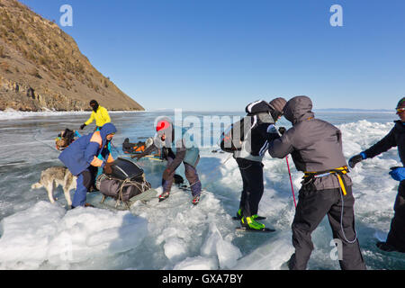 Baikalsee, Russland, März 24. Die Überfahrt durch den Spalt im Eis der Baikalsee großen touristischen Gruppe Menschen Eislaufen und Stockfoto