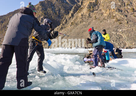 Baikalsee, Russland, März 24. Die Überfahrt durch den Spalt im Eis der Baikalsee großen touristischen Gruppe Menschen Eislaufen und Stockfoto