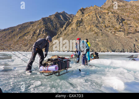 Baikalsee, Russland, März 24. Die Überfahrt durch den Spalt im Eis der Baikalsee großen touristischen Gruppe Menschen Eislaufen und Stockfoto