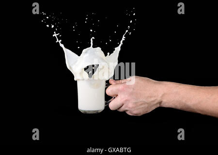 Mannes Hand hält eine Tasse Milch mit einem Schuss auf einem dunklen Hintergrund Stockfoto