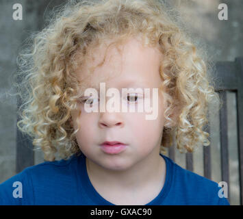 ein Porträt eines kleinen Jungen mit blonden lockigen Haaren Stockfoto