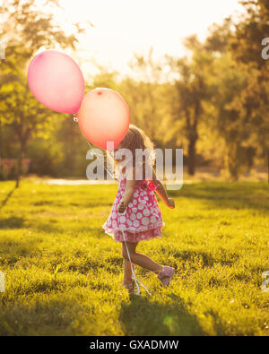 Kleines Mädchen mit Luftballons Spaziergänge im Park im Freien. Der Mensch ist nicht wiederzuerkennen. Stockfoto