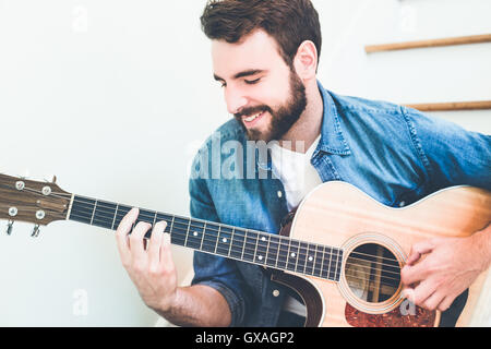 Hübscher junger Mann trägt eine Jeans Hemd klassische Gitarre zu spielen. Stockfoto