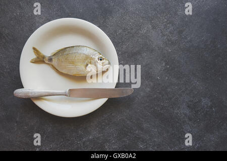 Fisch auf einem weißen Teller auf Zement-Hintergrund Stockfoto