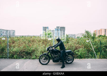 Ältere männliche Motorradfahrer tragen schwarze sitzt auf dem Motorrad unterwegs Stockfoto