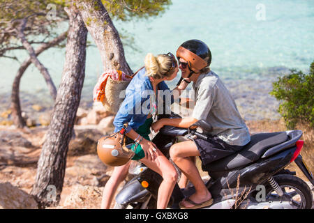 Romantische junges Paar auf Moped küssen an Küste, Mallorca, Spanien Stockfoto
