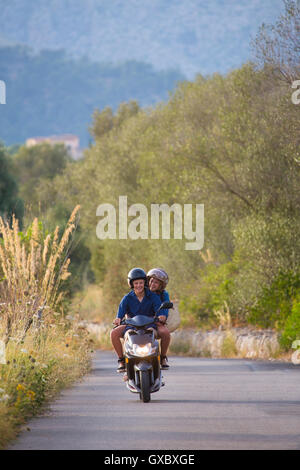 Junges Paar Reiten moped auf Landstraße, Mallorca, Spanien Stockfoto