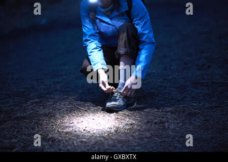 Weibliche Wanderer tragen binden Wanderschuh Stirnlampe Schnürsenkel in der Nacht Stockfoto