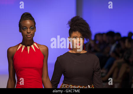 Designer, die zu Fuß über den Laufsteg mit einem Modell am Ende der Show ihres Collecton in der West Hall Olympia in London Stockfoto