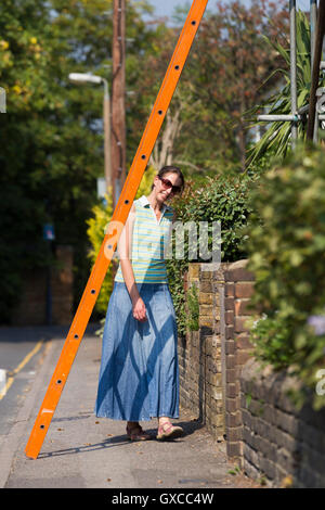 Fußgängerzone / Lady / junge Frau / Menschen / Person laufen unter einer Leiter und Pech in Twickenham, Greater London zu riskieren. UK Stockfoto