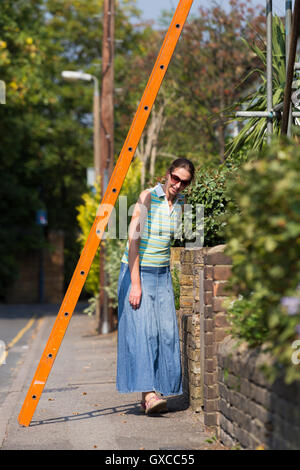 Fußgängerzone / Lady / junge Frau / Menschen / Person laufen unter einer Leiter und Pech in Twickenham, Greater London zu riskieren. UK Stockfoto