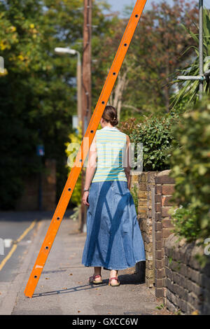 Fußgängerzone / Lady / junge Frau / Menschen / Person laufen unter einer Leiter und Pech in Twickenham, Greater London zu riskieren. UK Stockfoto