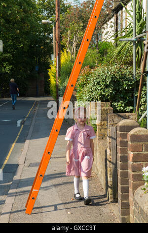 Fußgängerzone / junge Schulmädchen / Kind / Kinder in Uniform / Personen / Person zu Fuss unter Gerüst Leiter, Pech zu riskieren. UK Stockfoto